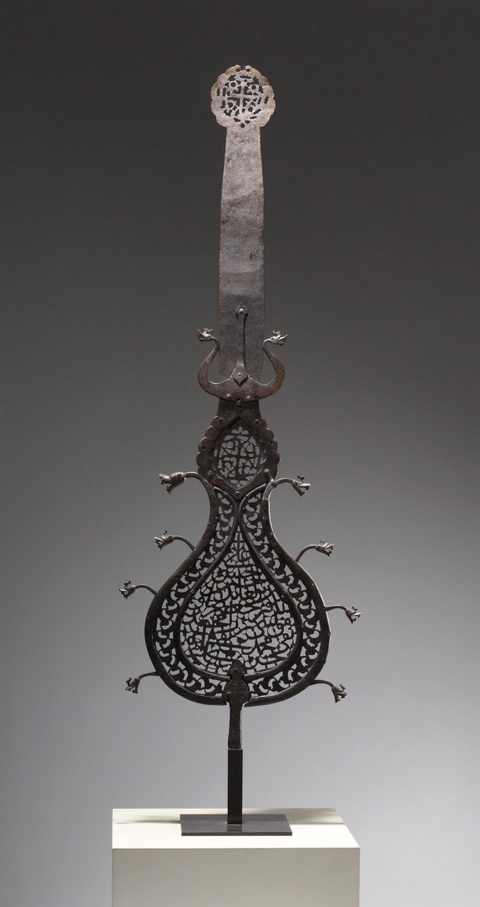 An Iranian, metal 'alam from the 17th century. The center and top contain calligraphy. Five dragon h