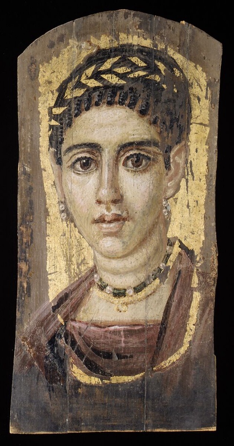 A portrait of a woman with dark hair and large round eyes. Wearing a gold wreath upon her head, she 