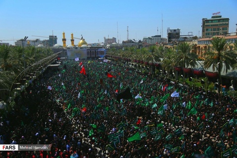 A palm-lined street, completely full of people wearing black clothing and waving green flags. The go