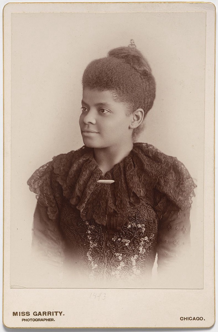 A sepia-toned photograph of a woman looking off-camera in a three-quarter pose. Her hair is in an up
