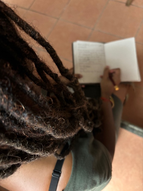 A color photo depicts the author, Mi’Jan Celie Tho-Biaz, writing in a leather bound journal, holding